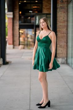 A model in a simple cocktail dress features a v-neckline with strappy back. Evening V-neck Backless Dress With Fitted Bodice, Evening V-neck Dress With Corset Back, A-line Dress With Ruched Bodice For Night Out, A-line Dress With Corset Back For Night Out, V-neck Mini Dress With Corset Back For Date Night, Evening V-neck Dress With Back Opening, Evening Dress With V-neck And Back Opening, Elegant A-line Mini Dress With Lace-up Back, V-neck Party Dress With Back Opening