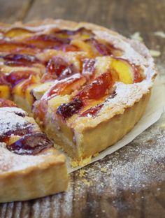 a pastry with fruit on it sitting on top of a wooden table