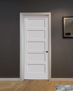 an empty room with a white door and rugs on the floor in front of it