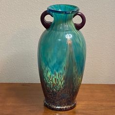 a blue vase sitting on top of a wooden table next to a brown and white wall