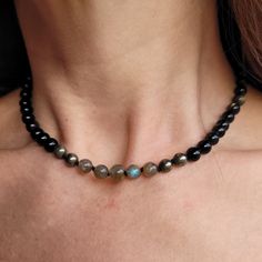 "Refine your style with this exquisite choker necklace, handcrafted with a striking combination of beaded gold obsidian, pyrite, and labradorite on black knotted silk.  Each bead is carefully selected for its natural variations, lending the piece a unique and nuanced identity. The black knotted silk provides a sophisticated backdrop for the shimmering beads, while the choker style adds a bold and contemporary touch to any outfit. Whether you're dressing up for a special occasion or elevating you Black Labradorite Spiritual Necklaces, Adjustable Labradorite Necklaces With Round Beads, Black Labradorite Jewelry For Gift, Polished Round Obsidian Bead Jewelry, Beaded Obsidian Jewelry Gift, Adjustable Labradorite Gemstone Beaded Necklaces, Obsidian Beaded Jewelry As Gift, Labradorite Beaded Jewelry As A Gift, Obsidian Beaded Jewelry Gift