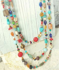 "Three pretty graduated strands of multi color, semi precious stones make up this long bold necklace. Just about every stone you can imagine, turquoise, garnet, lapis, pearls, chrysoprase, red coral, and carnelian, just to name a few. The stones are accented with Bali sterling silver fancy spacers. The necklace measures 33\" in total length. The longest strand measures 33\" the middle strand measures 30\" and the shortest strand measures 27\". All three strands are connected with a sterling silv Gem Stone Necklace, Semi Precious Stone Jewelry, Blue Sapphire Jewelry, Art Glass Jewelry, Semiprecious Stone Jewelry, Bead Projects, Necklace Colorful, Yellow Jewelry, Blue Dangle Earrings