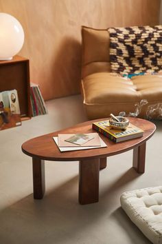 a coffee table with books on it in a living room next to a couch and ottoman