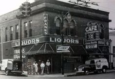 an old black and white photo of people standing in front of a liquor store on the corner of a street