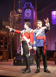 two men in uniform standing on stage with one holding his hand out to the other