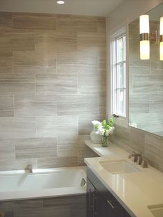 a bathroom with two sinks and a bathtub in front of a large mirror on the wall