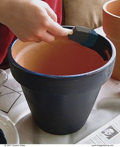 a person using a paint brush to decorate a pot