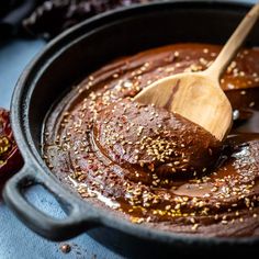 a wooden spoon in a black pot filled with chocolate sauce and sprinkles