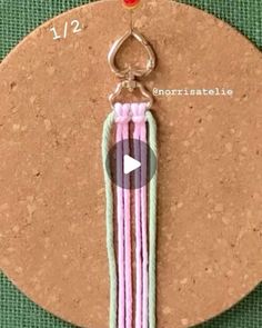 a pink and green keychain hanging from a cork board