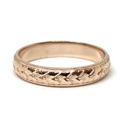 a rose gold wedding ring with leaves on it's sides and an engraved design in the middle