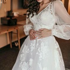 a woman in a wedding dress posing for the camera with her hands on her hips