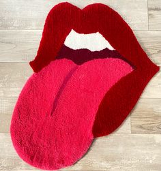 a rug with the shape of a red tongue on it's side, laying on top of a wooden floor