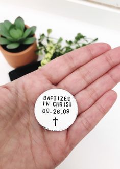 a hand holding a small white button with the words baptistized in christ on it