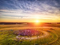 an aerial view of a large group of people in a field at sunset or sunrise