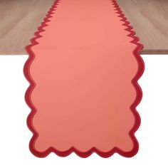 a long red table runner with scalloped edges on the top and bottom edge