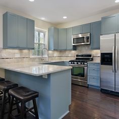 a kitchen with blue cabinets and stainless steel appliances