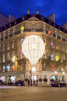 people are standing in front of a large building with balloons on it's side