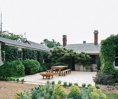 an outdoor patio with table and chairs surrounded by greenery on either side of the house