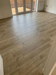 an empty room with wooden floors and sliding glass doors that lead to the outside patio