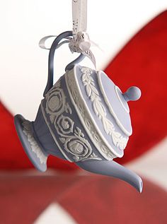 an ornament shaped like a teapot hanging from a string on a red and white background