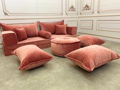 a living room filled with lots of pink furniture and pillows on top of each other