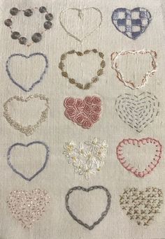 many different types of heart shaped beads on a white cloth with red and blue thread