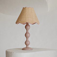 a pink lamp on top of a white table with a beige shade over the lampshade