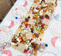 a table topped with lots of different types of snacks and desserts next to wine glasses