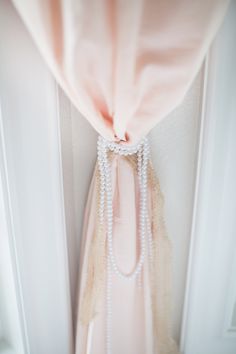 a pink curtain with pearls hanging from it's side