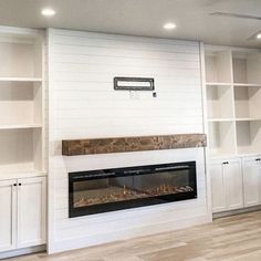 a living room with white bookcases and a fire place in the middle of it