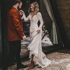 a man and woman standing next to each other in front of a mirror wearing wedding dresses