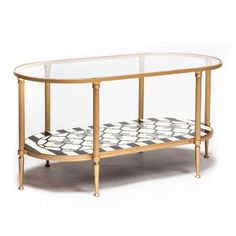 an oval glass table with gold frame and black and white designs on the bottom shelf