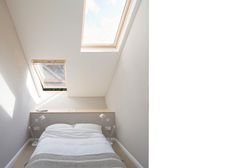 a bed sitting under a skylight in a bedroom