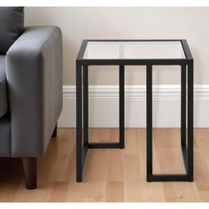 a glass table sitting on top of a hard wood floor next to a gray couch