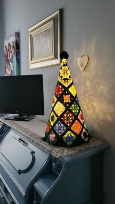 a very colorful knitted christmas tree sitting on top of a dresser next to a tv