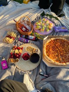 a pizza sitting on top of a blanket next to other foods and condiments