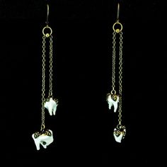 two white elephants dangling from chains on a black background in gold tone metal ear wires