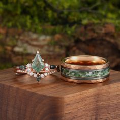 three different rings sitting on top of a wooden table next to another ring with green and white stones