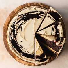 a chocolate cake with white frosting on a wooden platter, cut into slices