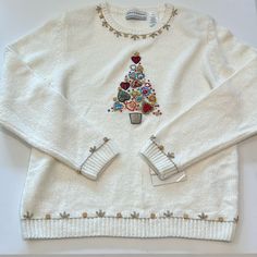 a white sweater with an embroidered christmas tree on the front and two matching cuffs at the bottom