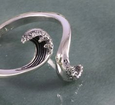 This sterling silver wave ring is simple, yet, intricate at the same time as two opposing waves come crashing towards each other. The waves are beautifully detailed and textural, illustrating the graceful flow of the ocean and the movement of the waves. Truly a ring for anyone who loves nature, especially the majestic essence of water. As pictured, this ring is a size 7 and adjustable. Waves Jewelry, Ocean Wave Engagement Ring, Wave Rings, Silver Wave Ring, Ocean-inspired Silver Rings For The Beach, Ocean Wave Ring, Adjustable Silver Ocean-inspired Rings, Sea Rings, Wax Carving Jewelry