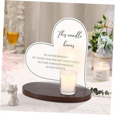 a candle is sitting on a table with a heart shaped sign