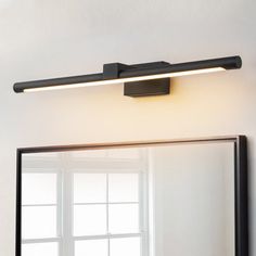 a bathroom mirror sitting next to a wall mounted light