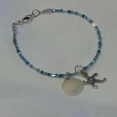 Beach Beauty Beaded Bracelet Blue, Turquoise & Clear Seed & Tube Beads With A North Carolina Seashell And Starfish Charms The Bracelet Measures 7.75" Coastal Cutie!!!!! New, Handmade By Me, With Love, For You!! (Please See The Beautiful Matching Necklace Listed As Well) Adjustable Blue Jewelry With Starfish Charm, Starfish-shaped Beaded Beach Jewelry, Adjustable Blue Starfish Jewelry, Blue Starfish Charm Jewelry For The Beach, Turquoise Beaded Bracelets With Starfish Charm, Blue Bracelet With Starfish Charm And Round Beads, Blue Bracelets With Starfish Charm And Round Beads, Starfish Shaped Beaded Bracelets For Beach Season, Blue Bracelets With Starfish Charm Ocean-inspired