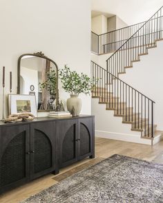 a living room area with a rug, table and stairs in the background on top of a hard wood floor