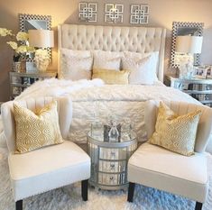 a white bed sitting in a bedroom next to two chairs and a table with lamps on it