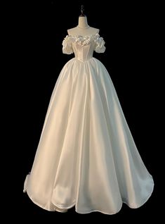 a white wedding dress on display in front of a black background