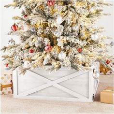 a white christmas tree with red and gold ornaments in a wooden box on the floor