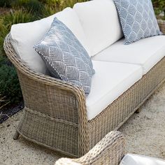 a wicker couch with blue and white pillows