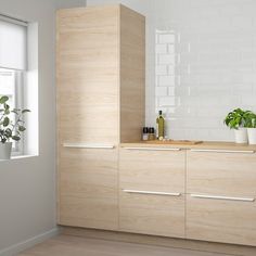 a kitchen with white brick wall and wooden cabinetry next to a potted plant